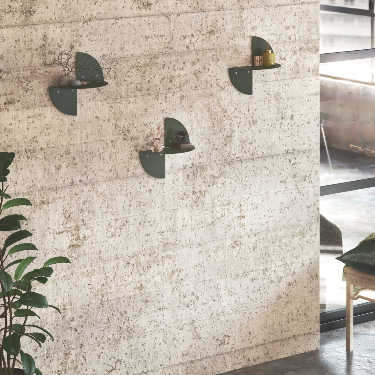 Decorative floating shelves in green, mounted on a textured wall, each holding small plants and decor items. A plant in a pot sits on the floor, adding to the stylish, modern arrangement.