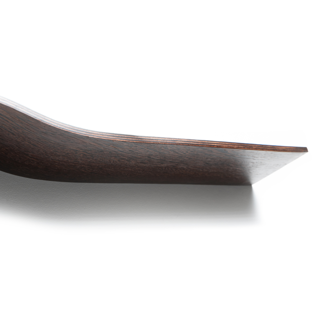 Close-up of a dark wooden shelf with a sleek, curved middle, set against a white background. The smooth finish of the wood and the visible grain emphasize the shelf&