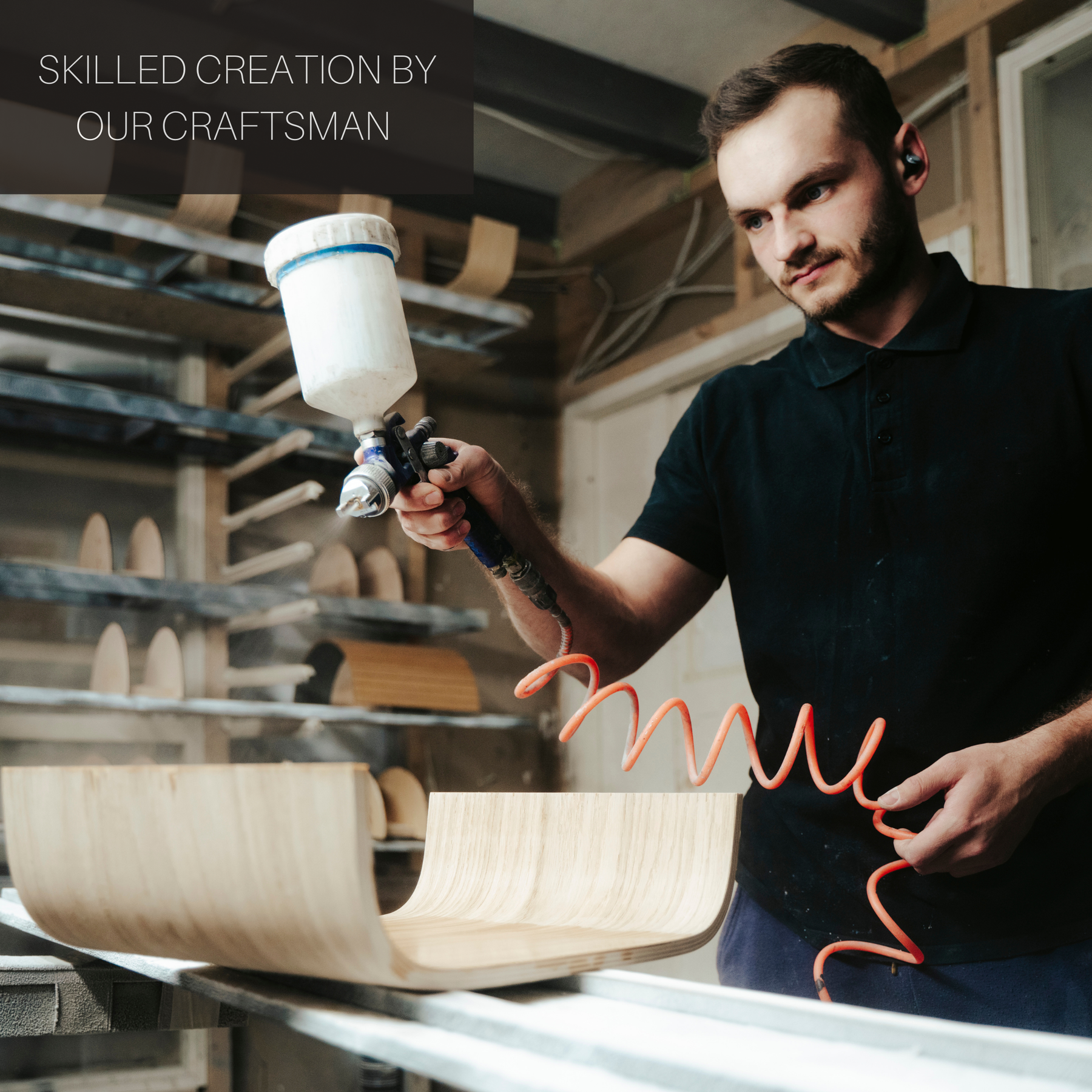 Craftsman using a spray gun in a workshop for wooden furniture