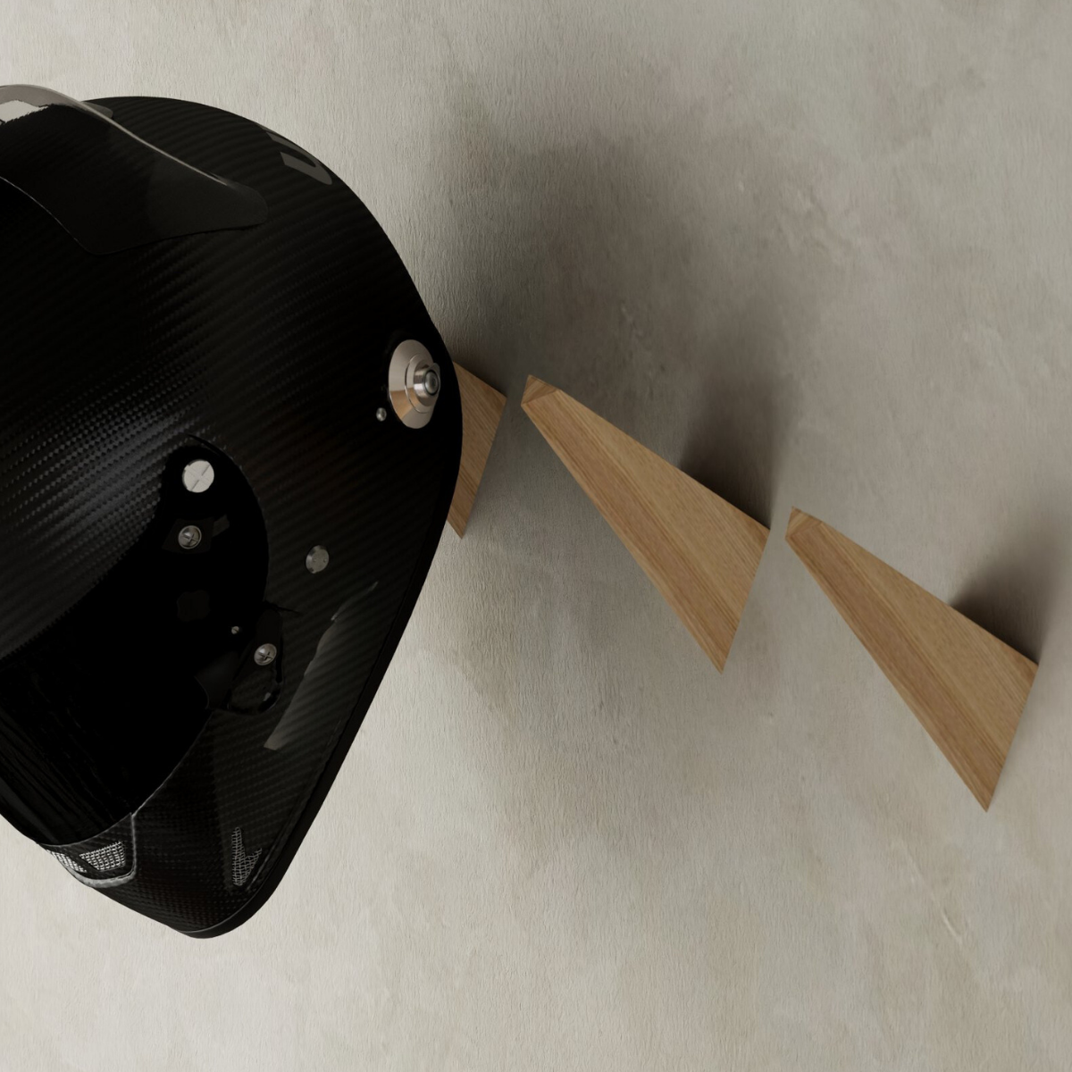 Close-up of triangular wooden wall hooks securely holding a black motorcycle helmet, mounted on a textured neutral wall.