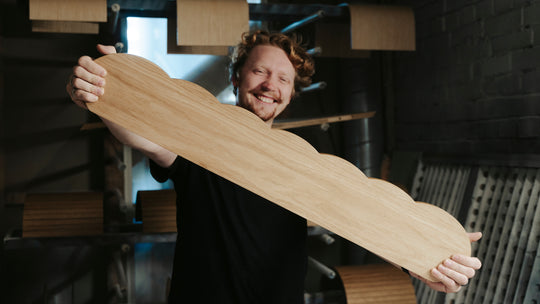 Cheerful EWART WOODS craftsman holding a wooden cloud design shelf