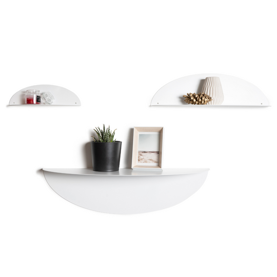Set of three white metal floating wall shelves in different sizes, holding decorative items like a potted plant, photo frame, and small vases, creating a minimalist and modern aesthetic.
