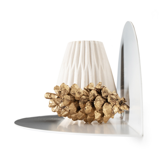 Close-up of a white ceramic vase and a gold-painted pinecone displayed on a sleek white metal floating shelf with an elliptical shape, showcasing a minimalist design.