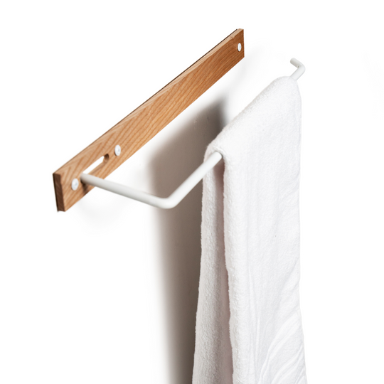 Wooden towel rack mounted on the wall with a white metal bar, visible screws, and a white towel hanging.