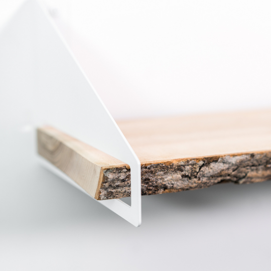 Close-up view of wooden shelf with tree bark and white geometric brackets