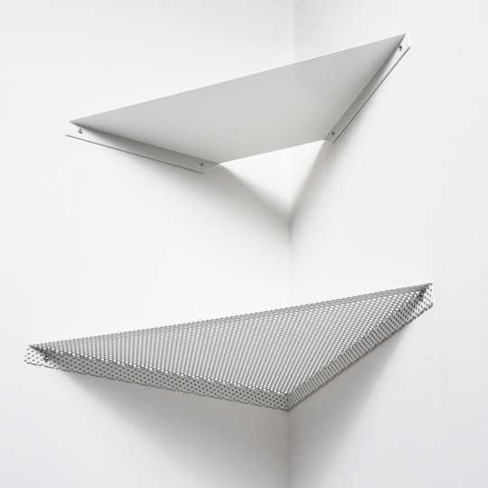 Two minimalist white wall-mounted shelves in a corner, one solid and the other perforated metal, arranged in a geometric style.