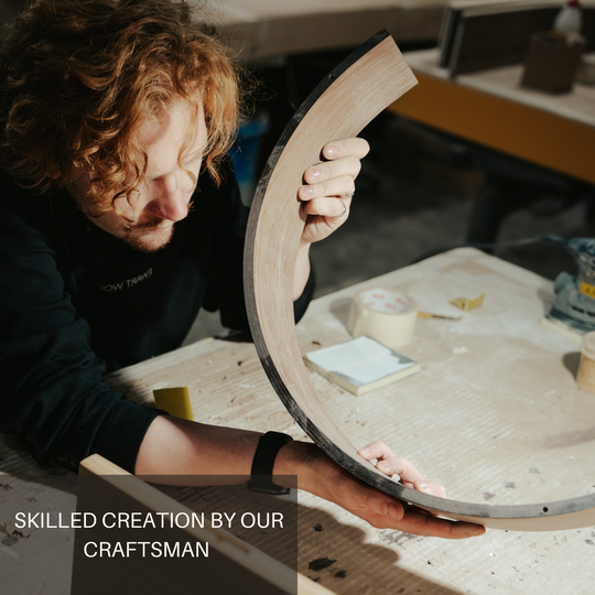 A craftsman from EWART WOODS holding a curved piece of wood, showcasing skilled craftsmanship in the workshop.