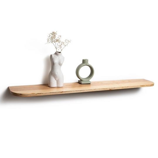Minimalist wooden shelf with a torso-shaped vase holding flowers and a circular green ceramic object. The shelf has a natural wood finish.