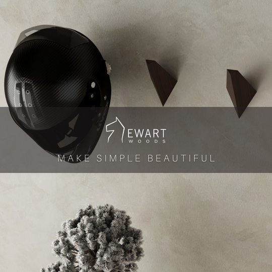 Top view of a black motorcycle helmet mounted on triangular wooden hooks, with the EWART WOODS logo and slogan &