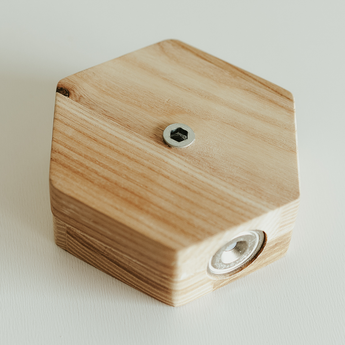 Close-up of the back of a hexagonal wooden key holder, showing a metal screw and mounting hardware, with visible natural wood grain patterns.