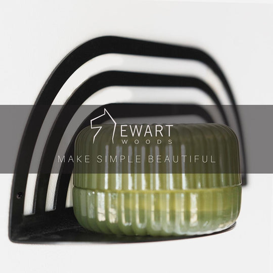 Arched metal shelf holding a ribbed, green container. The image features the Ewart Woods logo and the slogan "Make Simple Beautiful" displayed across the center.
