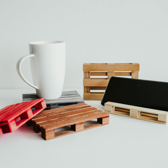 Different color variations for handmade wooden pallet coasters featuring smooth, polished slats and carefully crafted details, resting on a white surface.