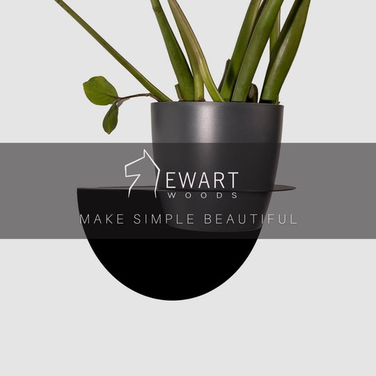 Modern black wall-mounted planter with a minimalist half-moon shape, securely holding a potted plant.