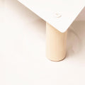 Close-up of a light wood cylindrical leg supporting a triangular white metal platform, secured with a screw.