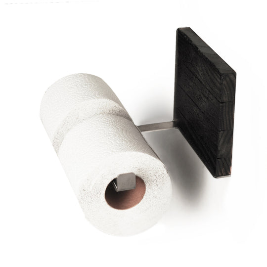 Close-up of a burned ash wood and stainless steel toilet paper holder with two rolls of toilet paper. The design features a sleek metal bar and textured wood