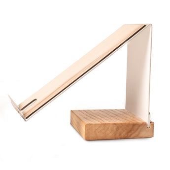 Side view of a modern, angular cell phone stand with a white metal frame and a rectangular wooden base, designed for hands-free viewing with an integrated charging slot.
