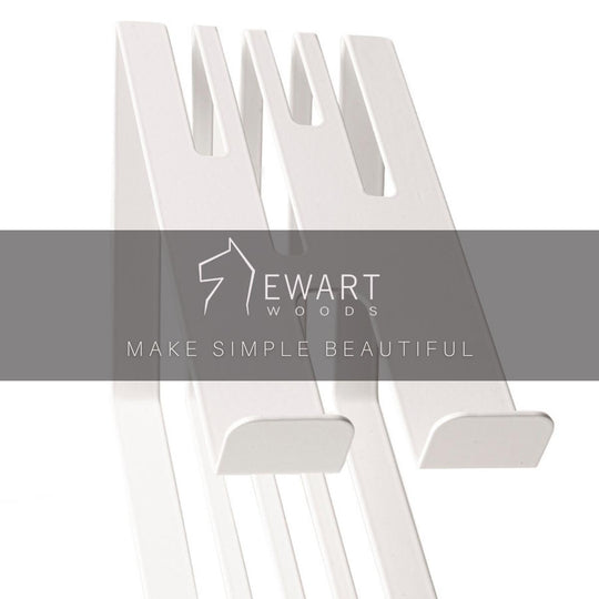 Close-up of a white metal phone holder with a slotted design, overlaid with the Ewart Woods logo and the slogan &