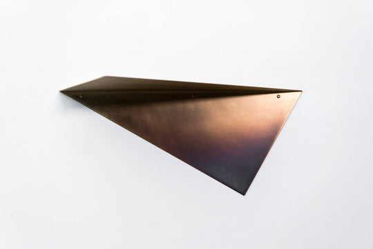 Close-up of a brushed copper triangular wall shelf with a sleek, minimalist design, showcasing clean lines and mounting screws.