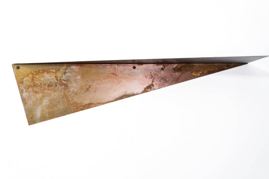 Close-up of a triangular metal shelf with a rustic, oxidized surface, showing texture and natural patina, with visible mounting holes.