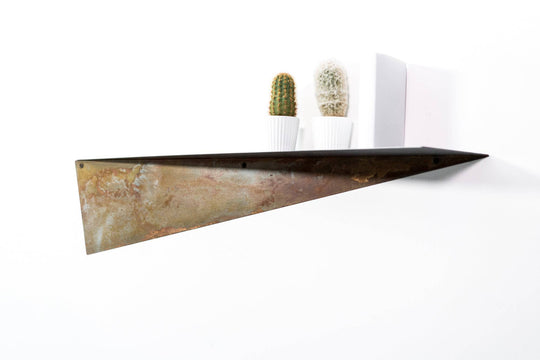 Stylish metal shelf with a rustic, oxidized surface, holding two potted cacti and a white book, set against a white wall.