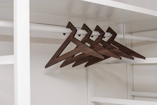 Wooden hangers in walnut finish with a geometric triangular design, hanging on a closet rod.