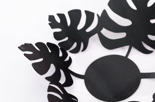Close-up of a sleek black metal bowl featuring tropical leaf cutouts.