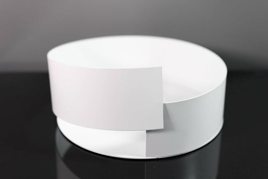 Sleek white metal bowl featuring a minimalist overlapping design, displayed on a glossy black surface for a modern aesthetic.