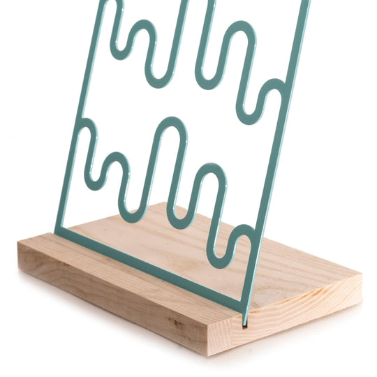 Turquoise wave-patterned metal jewelry holder on a natural wood base.