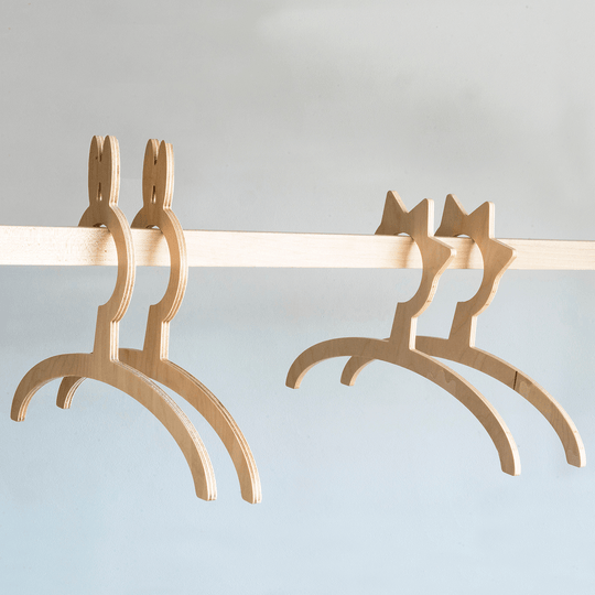 Close-up of four smooth, light wood hangers shaped like animals, with a natural grain texture, designed for children&