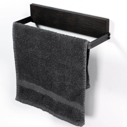 Black metal towel rack with a dark wooden backing, holding a neatly folded gray towel.