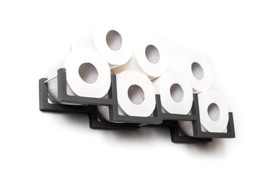 Close-up of a grey geometric wall-mounted organizer with square frames, holding several rolls of toilet paper in a modern arrangement