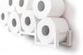 Close-up of a white wall-mounted toilet paper holder, holding seven rolls of toilet paper. The holder has a unique geometric design with individual frames for each roll.