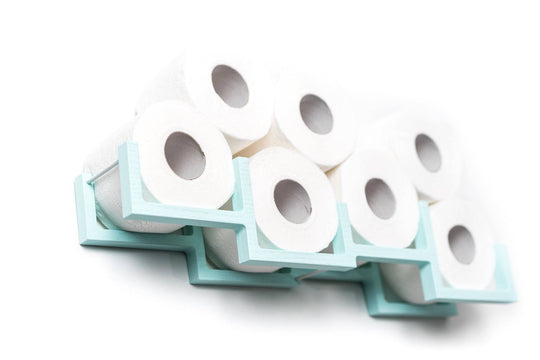 Close-up of a light blue wall-mounted toilet paper holder, holding seven rolls of toilet paper. The holder has a unique geometric design with individual frames for each roll.