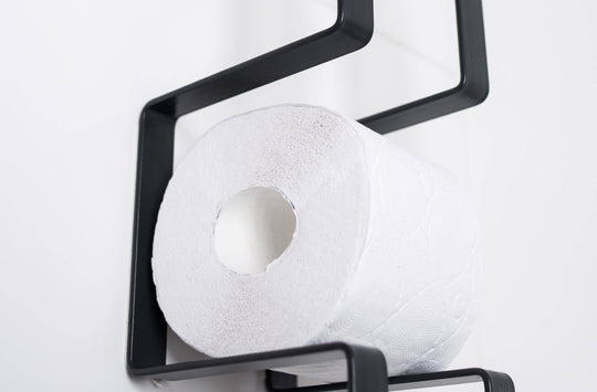 Close-up of a wall-mounted black toilet paper holder with a geometric design, displaying one roll of toilet paper.