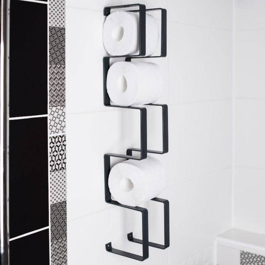 Wall-mounted black toilet paper holder with a unique geometric design, displaying three rolls of toilet paper in a stacked arrangement.