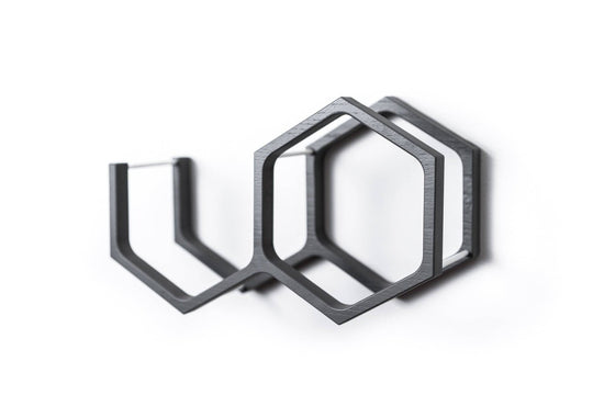 Close-up of a wall-mounted gray mini honeycomb toilet paper holder, displaying two rolls of toilet paper. The holder features a textured wood surface, highlighting the natural grain in a modern design.