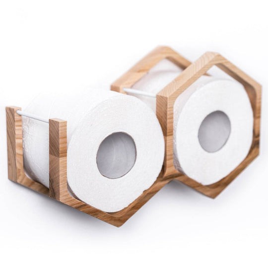 Close-up of a wall-mounted mini honeycomb wooden toilet paper holder, displaying two rolls of toilet paper. The holder features a textured wood surface.