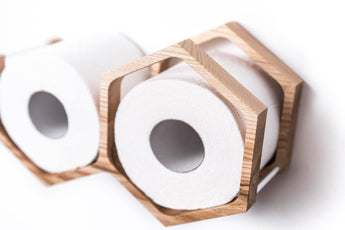 Close-up of a wall-mounted mini honeycomb wooden toilet paper holder, displaying two rolls of toilet paper. The holder features a textured wood surface, highlighting the natural grain and geometric design.
